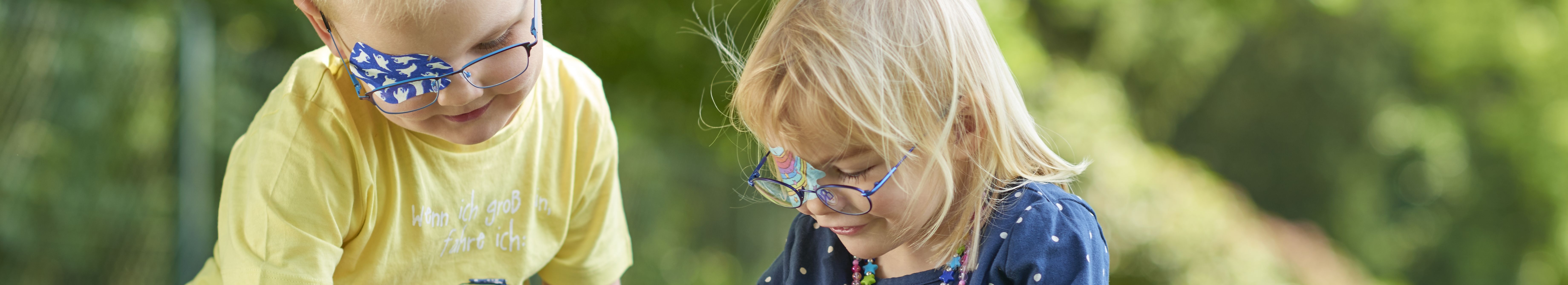 Kopafbeelding spelende kinderen met ORTOPAD®-oogpleisters spoken en regenbogen