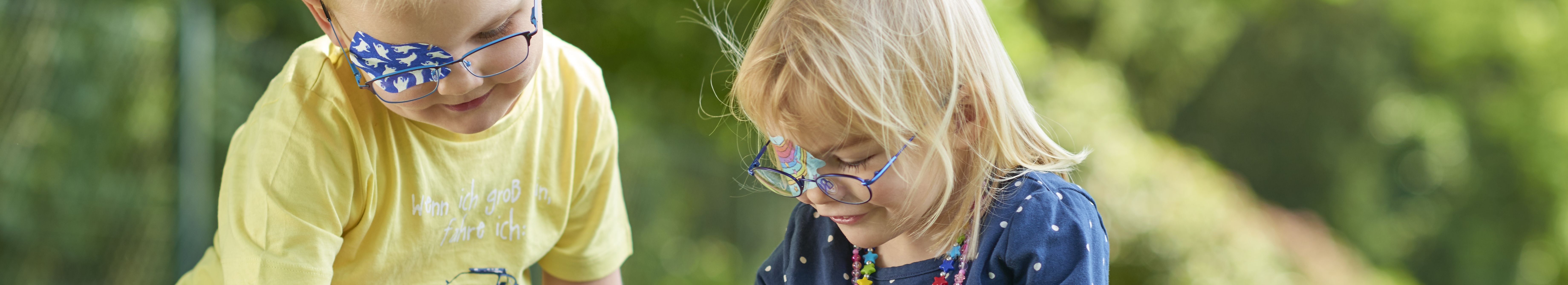 Kopafbeelding spelende kinderen met ORTOPAD®-oogpleisters spoken en regenbogen