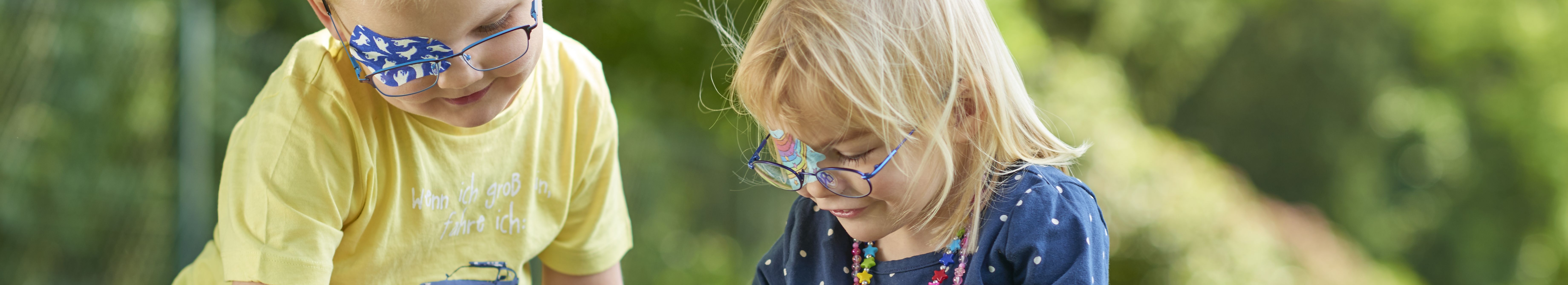Kopafbeelding spelende kinderen met ORTOPAD®-oogpleisters spoken en regenbogen
