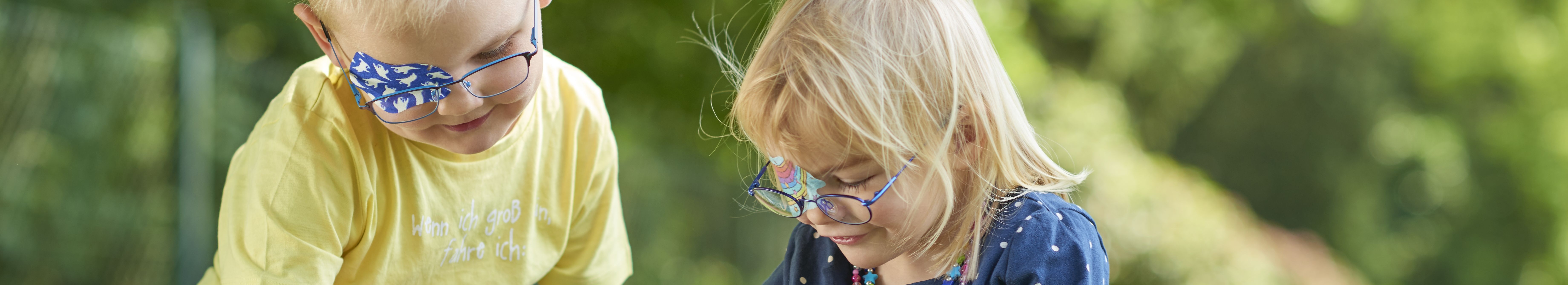 Kopafbeelding spelende kinderen met ORTOPAD®-oogpleisters spoken en regenbogen